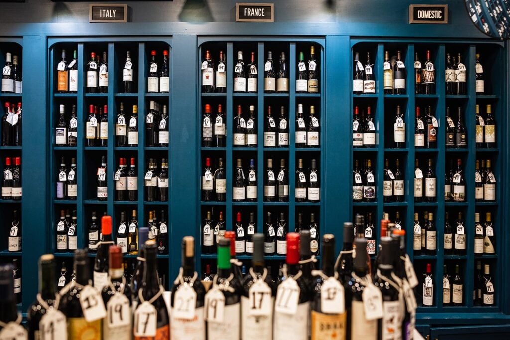 Many bottles of wine are lined up and displayed at a local wine shop. 