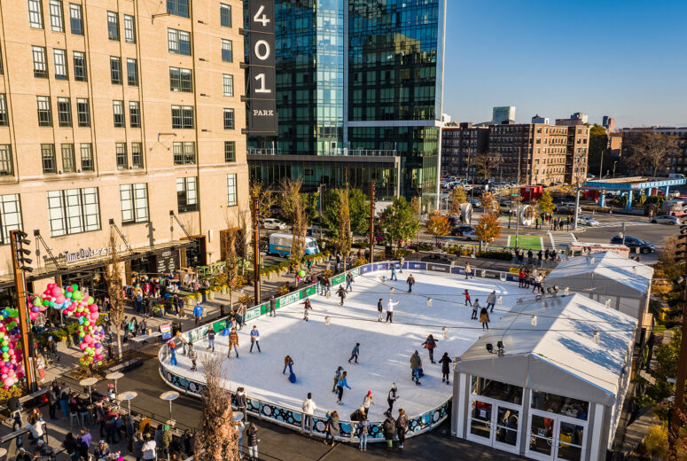 An aerial view of The Rink at 401 Park showing people ice skaing and hanging out around the ice rink eating and drinking.