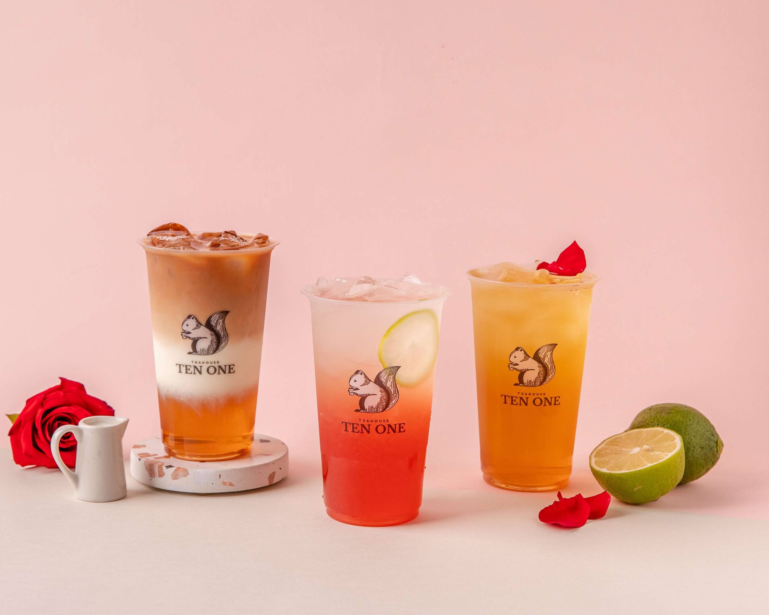 Three iced tea drinks with roses and limes on a pink background.