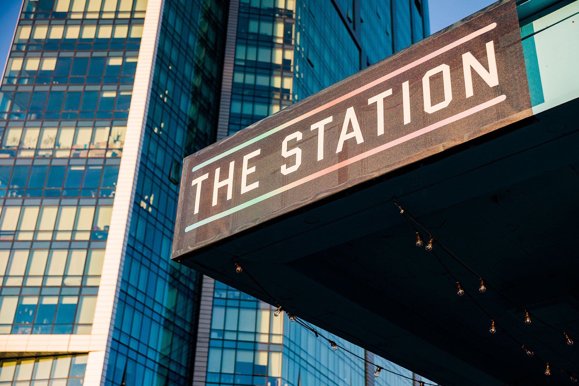 An edge of a building in the city with a sign on it that reads The Station.