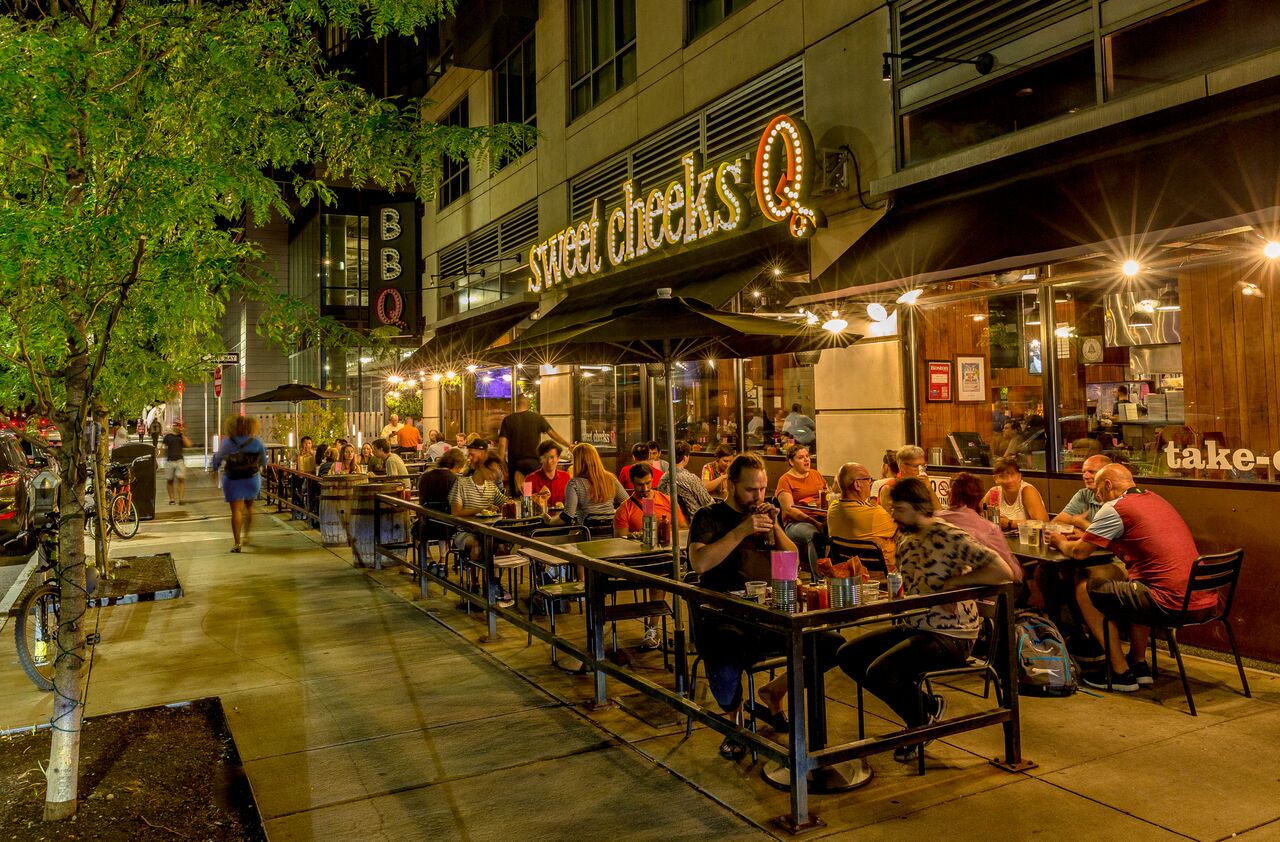 A bustling outdoor restaurant patio at the restaurant Sweet Cheeks Q.
