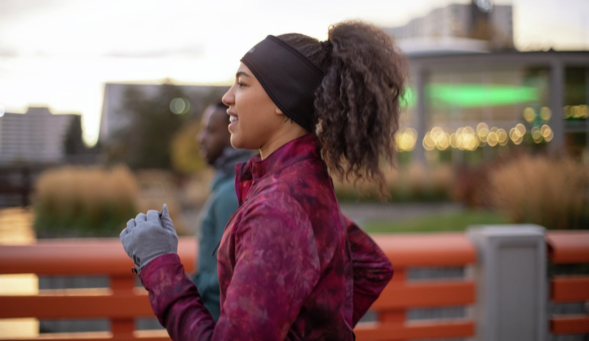 A young woman is dressed for cold weather as she runs outside in an urban environment.