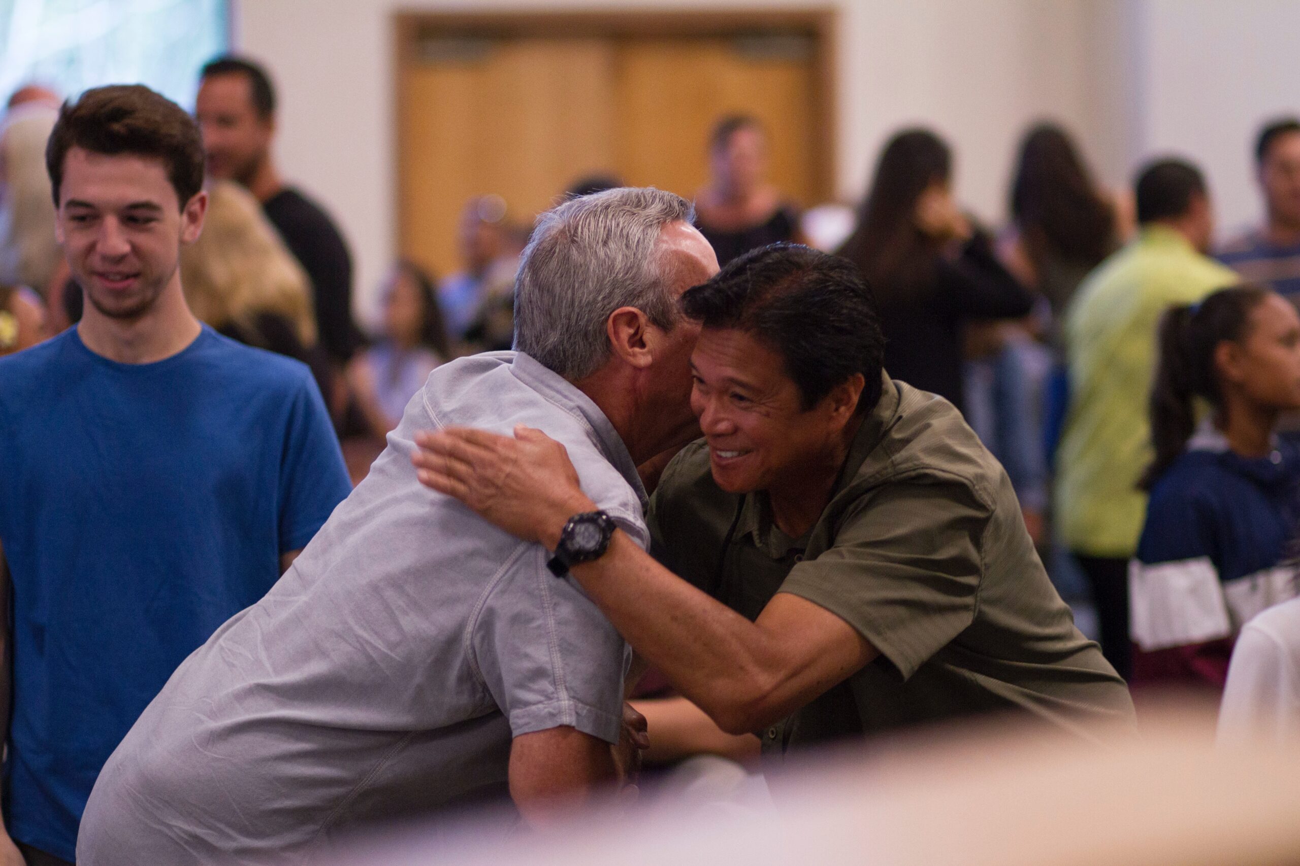 Two men embrace and share a conversation with each other at a community center.